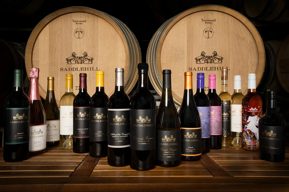 Saddlehill Winery's range of wines lined up in front of two oak barrels in the cellar