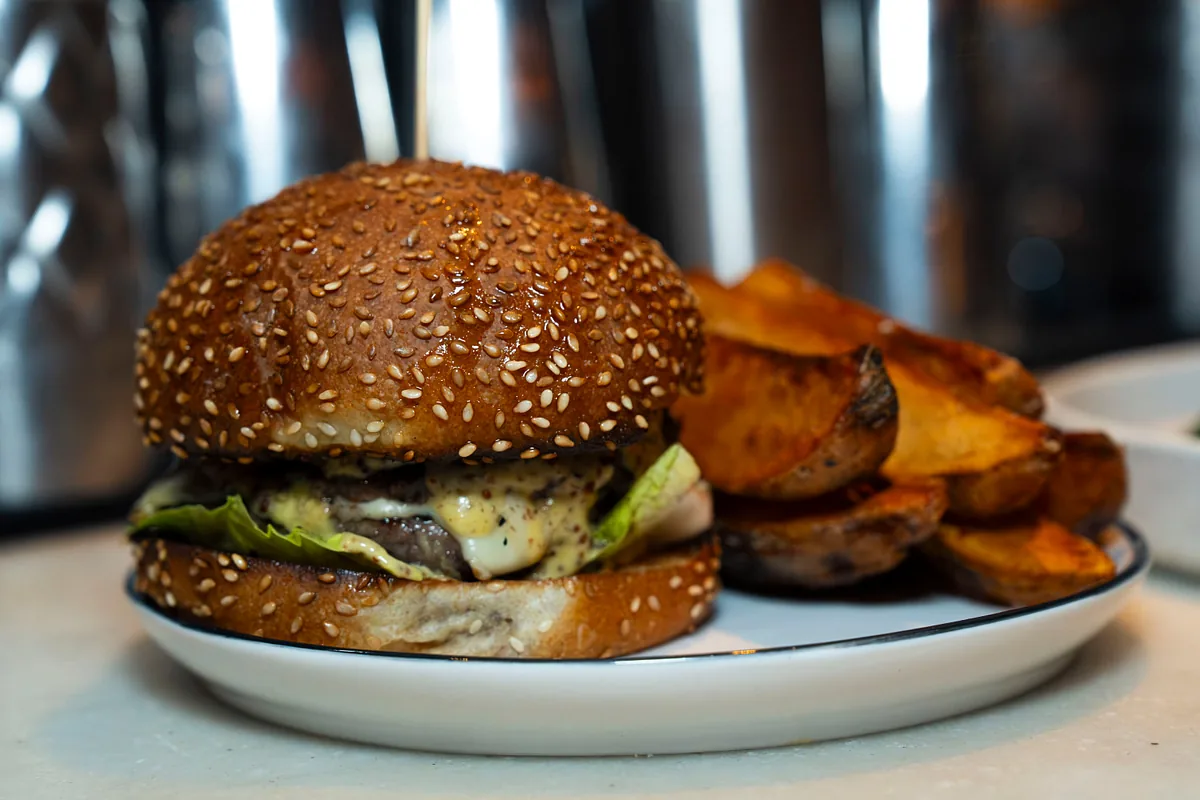 Burger on a sesame bun served with roasted potatoes