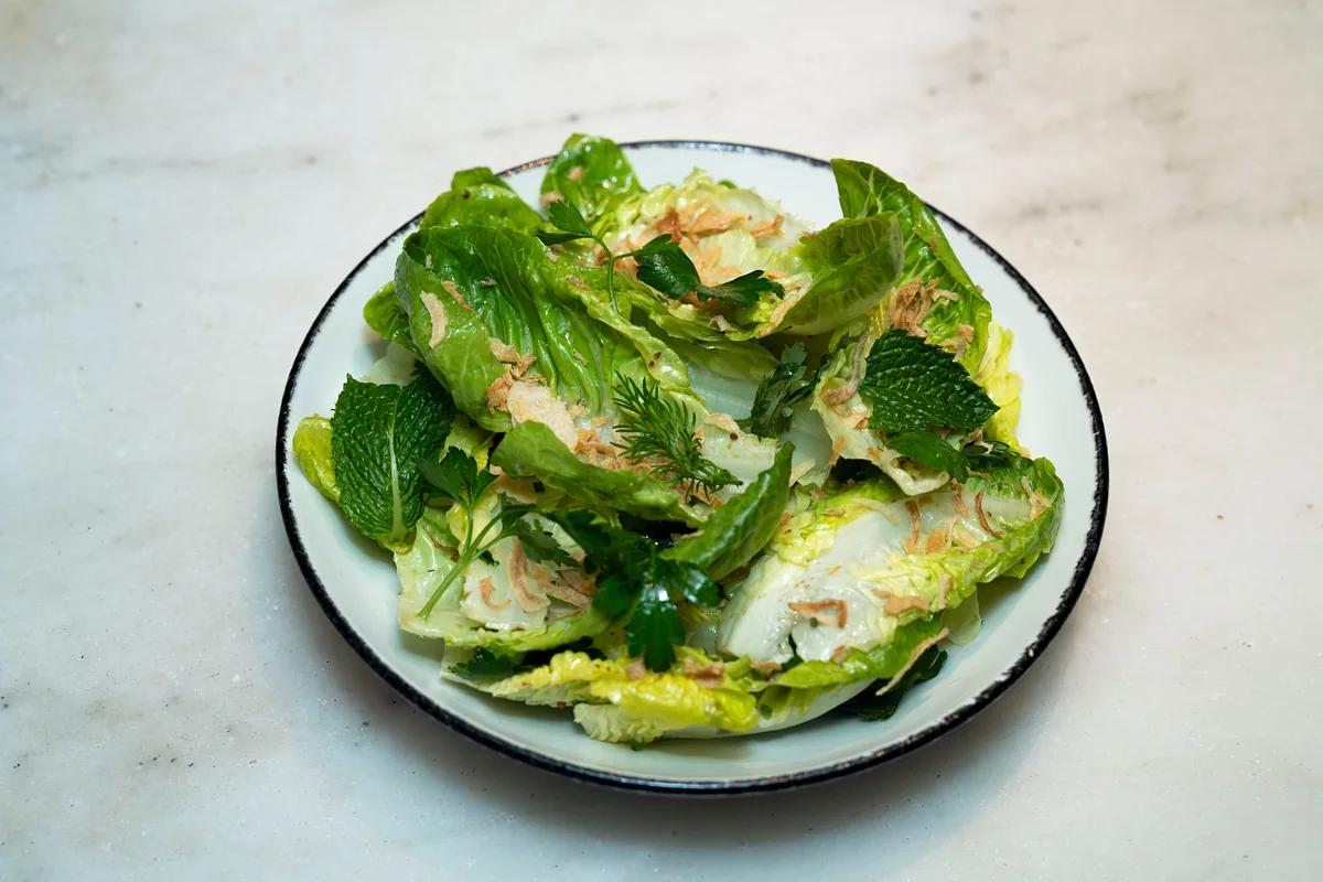 Overhead of a dressed green salad with shaved cheese