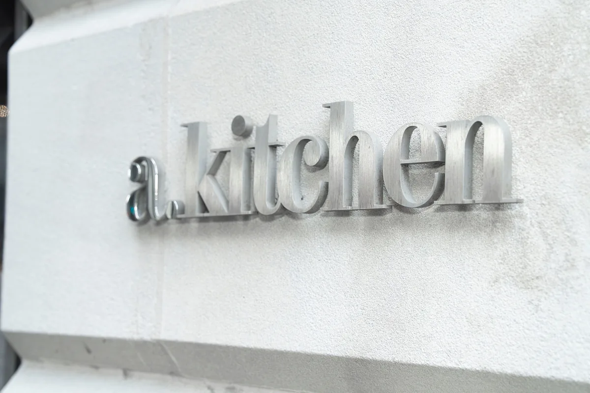 Brushed metal a.kitchen lettering mounted on a stone wall