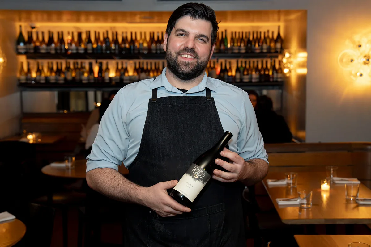 Member of the floor team presenting a bottle of wine in the dining room