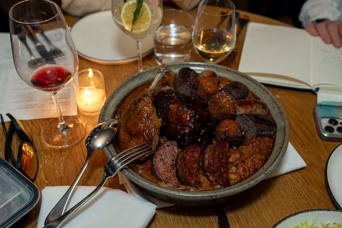 Table mid-service with wine, candles and a shared dish