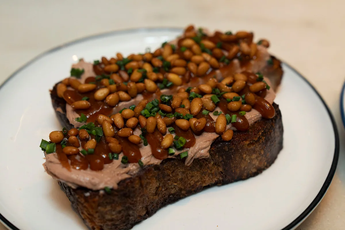 Thick toast topped with beans, crab and herbs on a dark plate