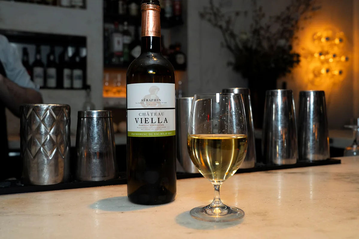 Bottle of white wine and a poured glass on the bar
