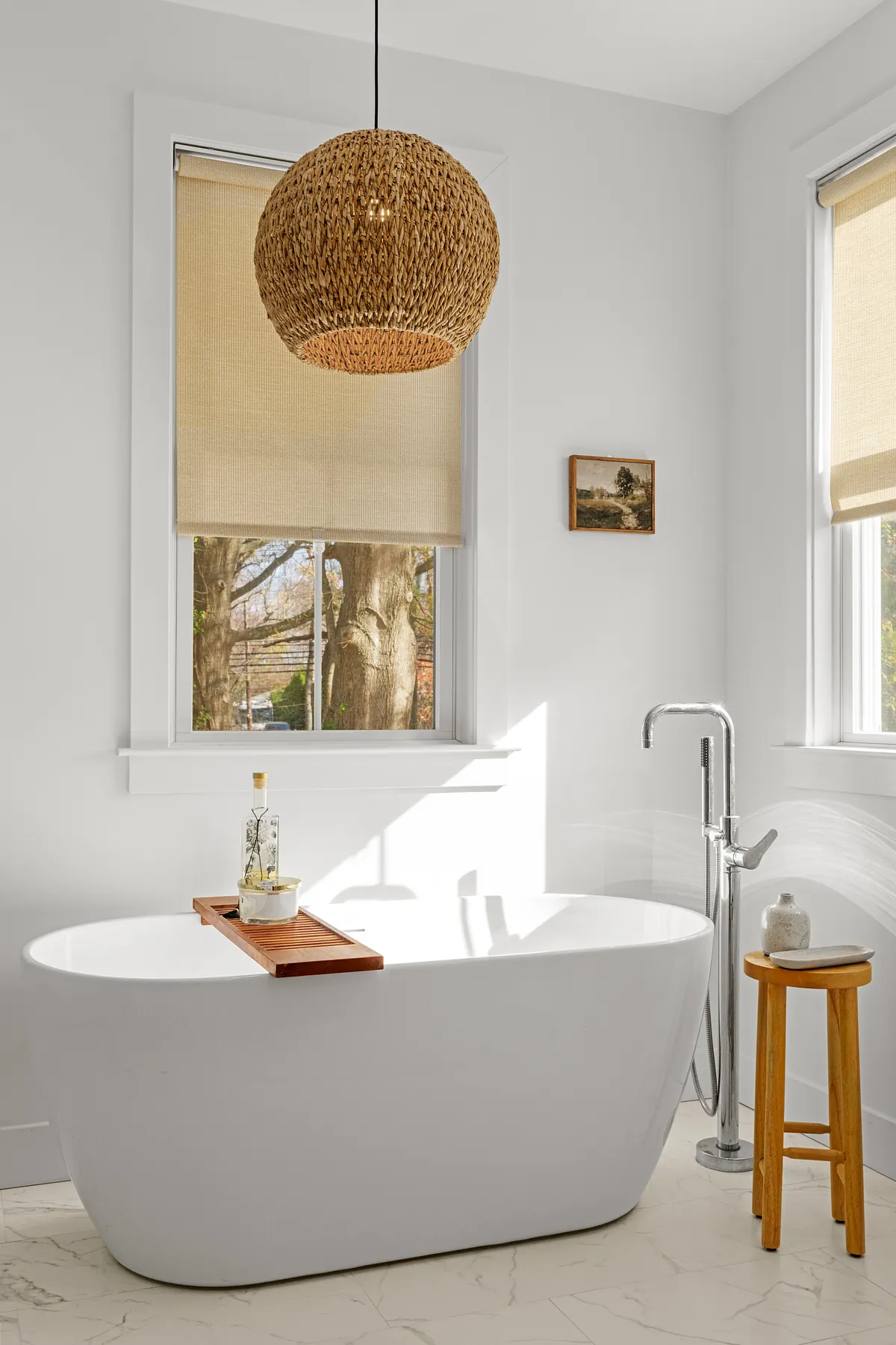 Oval soaking tub with a floor-mounted filler under a woven rattan pendant