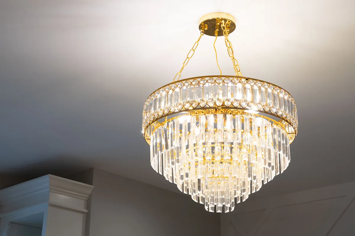 Tiered crystal and brass chandelier hanging from a white ceiling