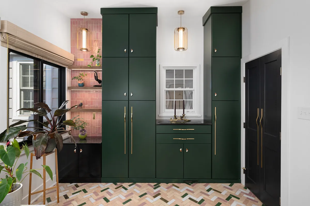Deep green built-in cabinetry over a pink and green herringbone tile floor