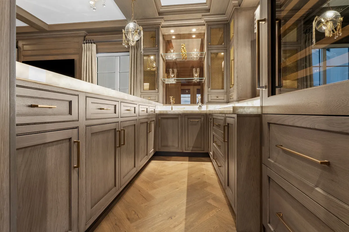 Run of oak bar cabinetry with brass pulls over a herringbone wood floor