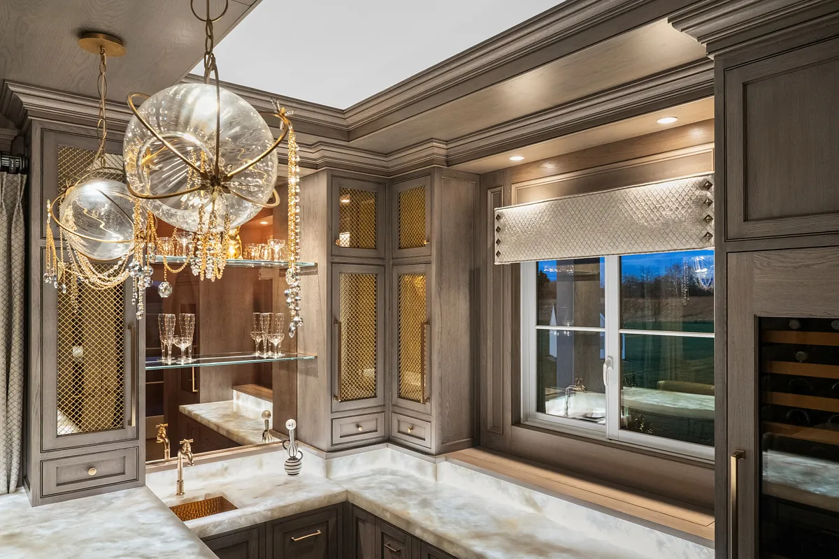 Backlit onyx bar counter beneath a glass globe chandelier and glazed cabinets