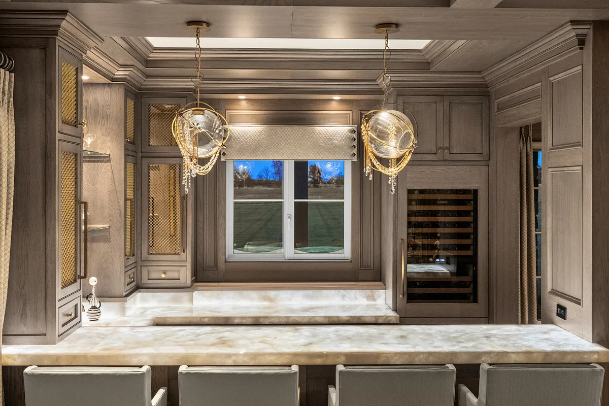 Bar wall with a wine refrigerator, glazed display cabinets and twin pendants