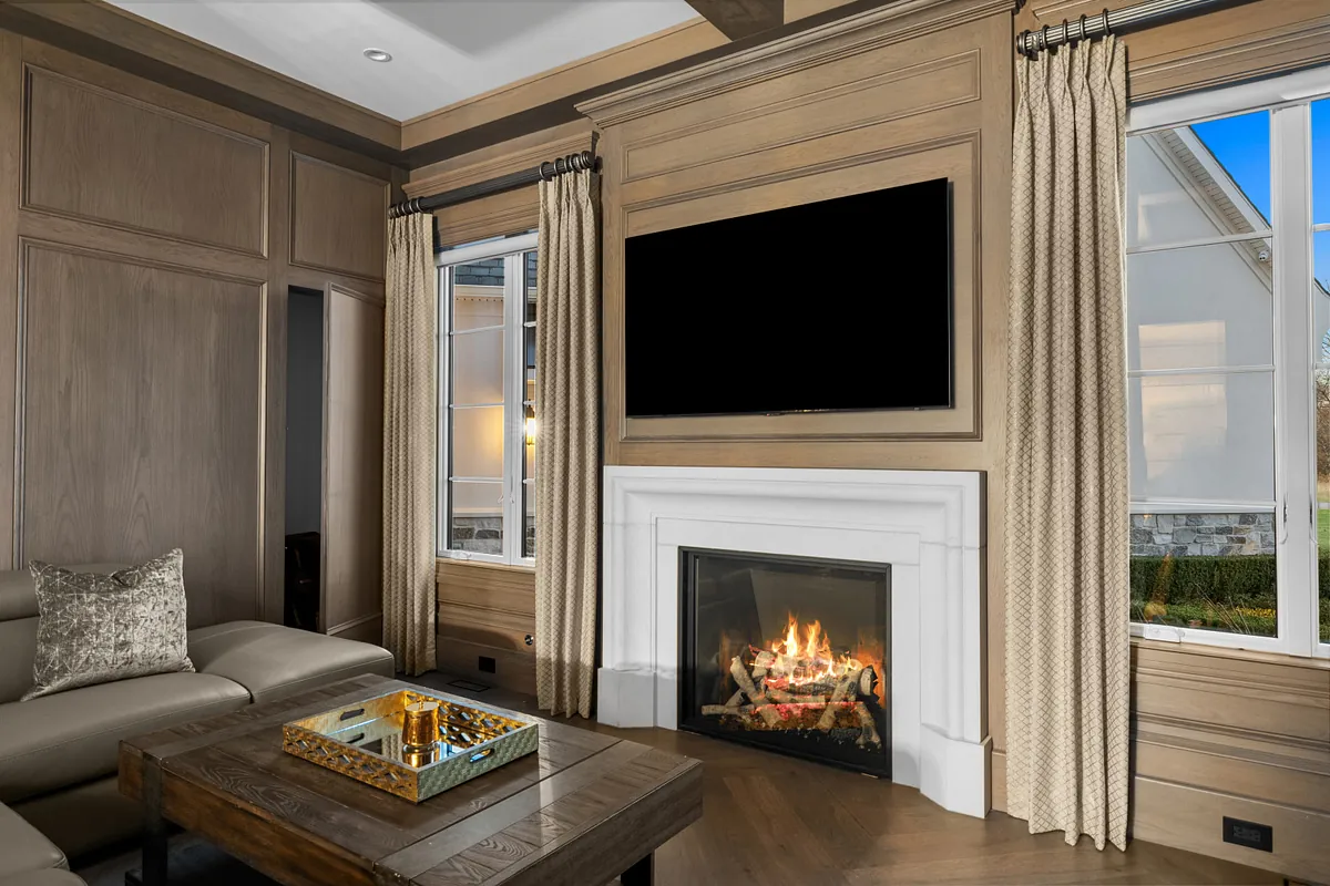 White fireplace surround set into oak wall panelling beneath a mounted television
