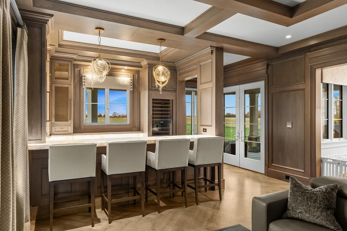 Home bar with upholstered stools, glass pendants and French doors to the garden