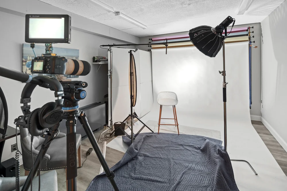 Shooting bay set up with a white seamless backdrop, lighting on booms and a camera on a tripod