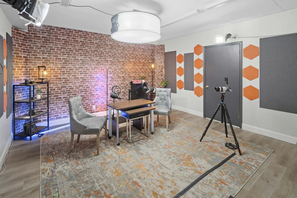Interview room with an exposed brick wall, seating either side of a table and acoustic panels