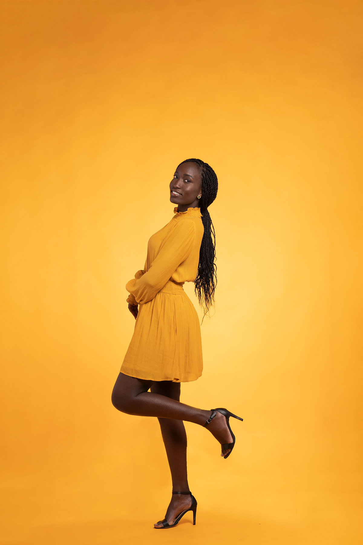 Full-length studio portrait against a vivid golden background