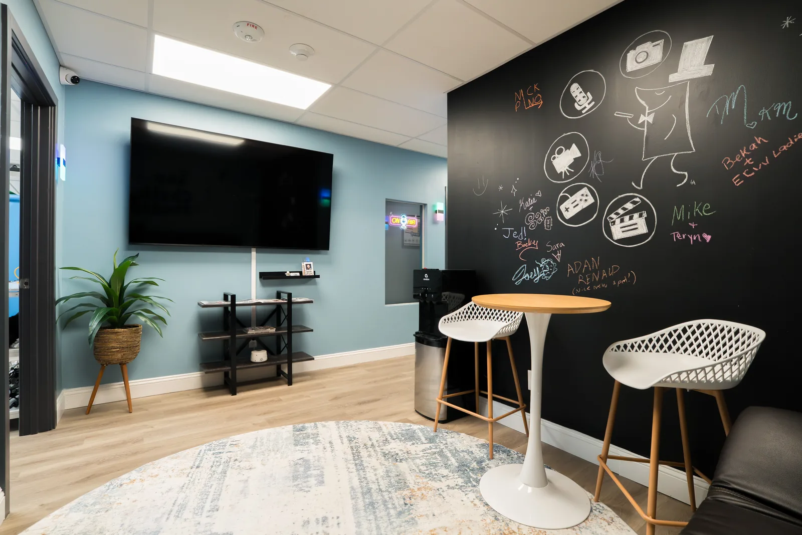 Lounge area with a wall-mounted screen, high stools and a round table for reviewing work