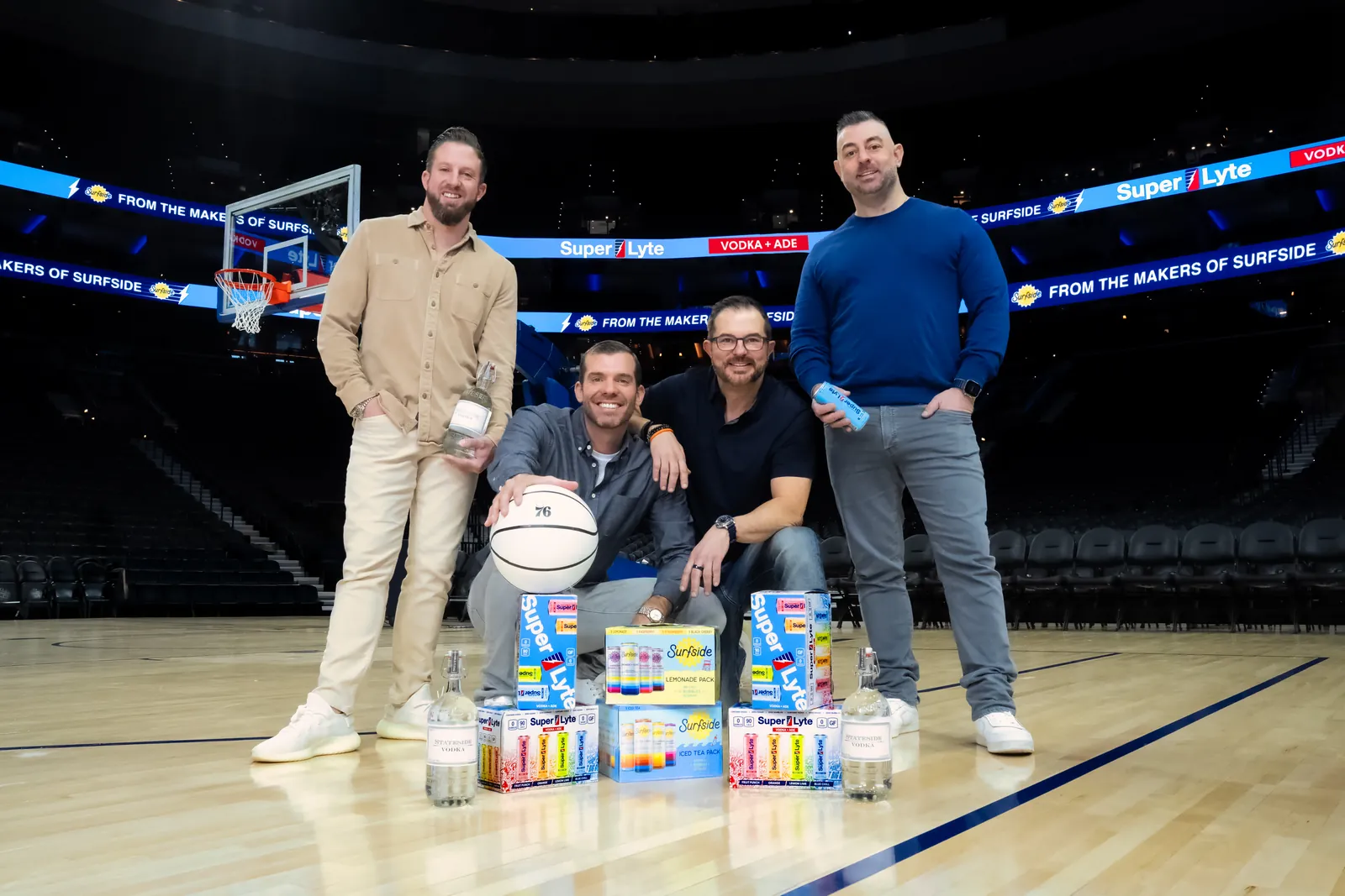 The Super Lyte team on a pro basketball court with a basketball, cans and 12-packs, Super Lyte ads running on the arena ribbon boards behind